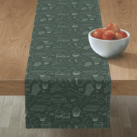 A repeat pattern of baking elements, like cupcakes, pies, cookies, bread, whisks, rolling pins, measuring spoons, eggs, sprinkles, chocolate, flour and sugar drawn in outlines in a cute cartoon style, in mint on a dark green background. The pattern is being demoed on a long narrow table runner