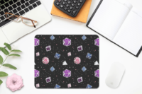 A repeating pattern of 7 Dungeons and Dragons Dice in Genderfluid Pride Flag colors: Purple, white, blue, and pink on a black background. It is demoed on a rectangular mousepad with rounded corners on a desk next to a pink flower.