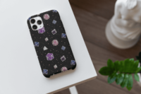 A repeating pattern of 7 Dungeons and Dragons Dice in Genderfluid Pride Flag colors: Purple, white, blue, and pink on a black background. It is demoed on an iPhone 14 Pro Max sitting on a white table.