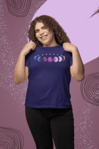 7 phases of the moon in a gradient of the genderfluid pride colors: blue, black, purple, white, and pink. It is demoed on a navy shirt on gender nonconforming person showing off their shirt happily.