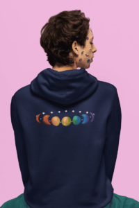 7 phases of the moon in a gradient of 7 colors of the rainbow. It is demoed on the back of a navy hoodie on a queer man with turquoise pants and stickers on his face.
