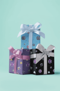 Three types of wrapping paper with a repeat pattern of 7 Dungeons and Dragons Dice, one in asexual Pride colors on black paper, in rainbow colors on purple, the third in transgender pride colors on blue paper. They are demoed on birthday presents.