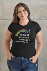 A cartoon of a smiling blue star at the end of a rainbow. Below in blocky white letters it says Yes Thank you I have tried yoga please suggest literally anything else in all caps. The design is demoed on a black T-shirt on a cheerful brunette woman.