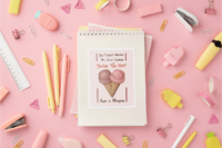 A 4x6 in sticker with a pair of pink and orange ice cream cones covered in sprinkles angled to create a heart. In brown and orange it says You could never be ice cream, you are too hot, and a person. It is on a notebook surrounded by cute pink and yellow office supplies and plastic ice cream bars.