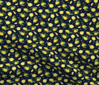A repeat pattern of lemons, lemon slices, and lemon wedges, interspersed with green leaves, ferns, small dark and light blue flowers. The background is black with small blue dots. The pattern is demoed in a small size on a piece of rippling fabric.