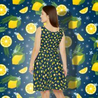 A brunette woman shown from the back wearing a dark blue, sleeveless skater dress with a repeat pattern of yellow lemons, green fronds and leaves, and tiny blue flowers. The lemons are whole, halved, and quartered in a ditsy pattern.